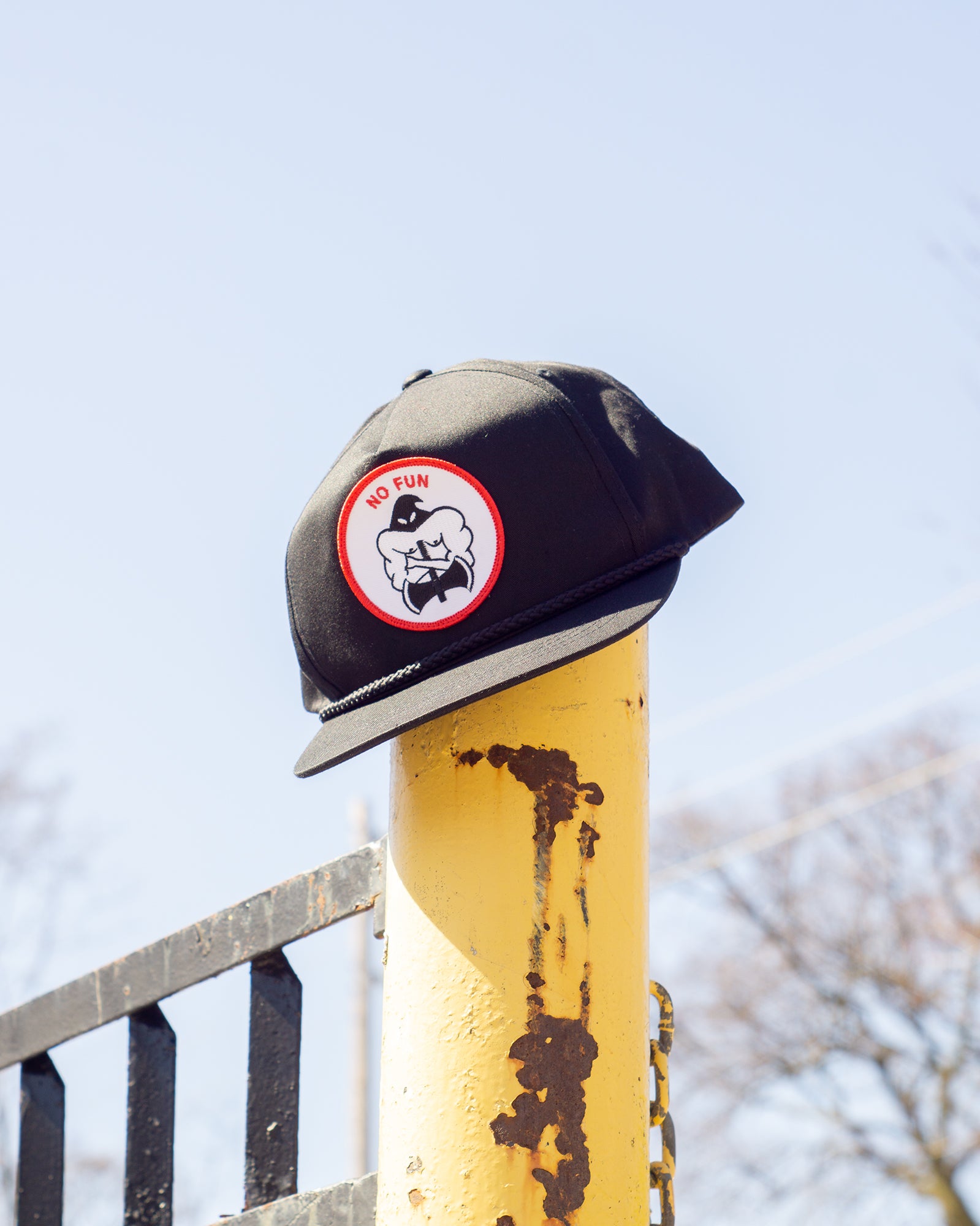 Photo of the "NO FUN®" X "Crawling Death" collaboration black, strapback hat.  The hat features a white patch with red embroidered border.  The embroidered graphic on the patch is a black and white executioner, with red "NO FUN®" logo.