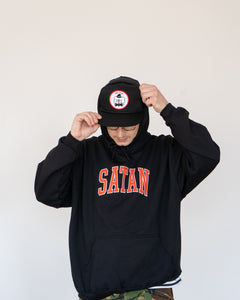 Photo of the "NO FUN®" X "Crawling Death" collaboration black, strapback hat.  The hat features a white patch with red embroidered border.  The embroidered graphic on the patch is a black and white executioner, with red "NO FUN®" logo.  This photo features a model in a hoodie wearing the hat.