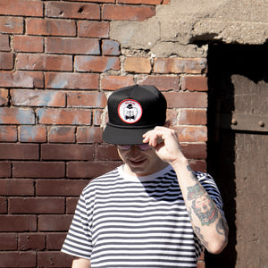 Photo of the "NO FUN®" X "Crawling Death" collaboration black, strapback hat.  The hat features a white patch with red embroidered border.  The embroidered graphic on the patch is a black and white executioner, with red "NO FUN®" logo.