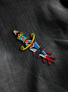 "Dagger" two-part embroidered iron-on patch designed by Brandon Ing. Patch is of traditional tattoo flash drawing of a dagger, split into two halves. One half is the blade, and the other half is the handle. Patch is multi colored, photographed against a leather jacket texture.