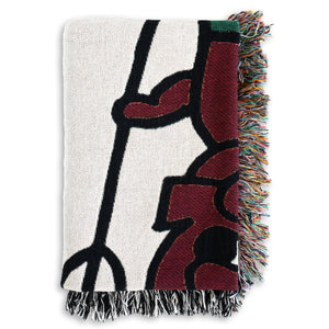 The "Devil" Woven Blanket by No Fun®.  The blanket is folded to better showcase the detail of the woven design.  Part of the devil's face, body, and the pitchfork are visible.